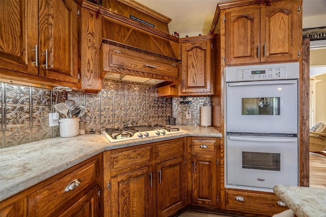 kitchen with stainless steel gas cooktop, double oven, and backsplash