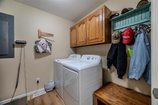 laundry area featuring cabinets, washer and clothes dryer, electric panel, and light hardwood / wood-style floors