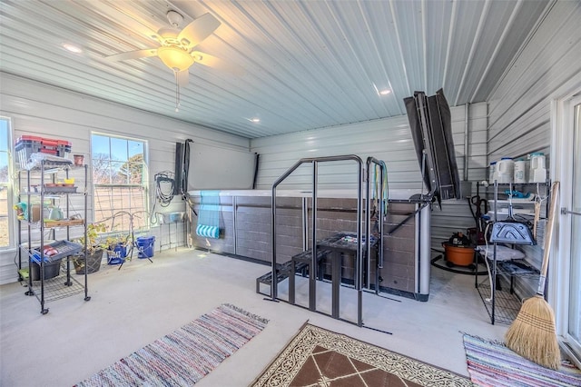 interior space with ceiling fan and wooden walls