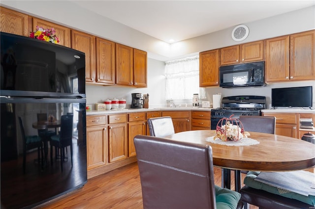 kitchen with sink, black appliances, and light hardwood / wood-style flooring