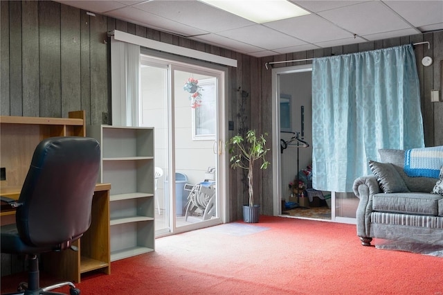 office area featuring wood walls, carpet flooring, and a paneled ceiling