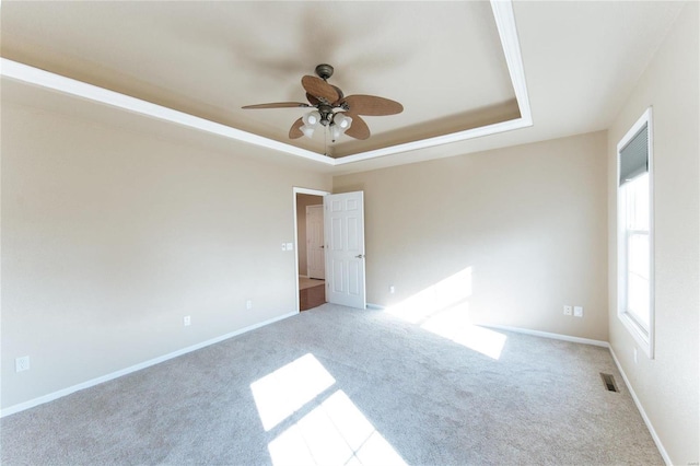 unfurnished room featuring light carpet, ceiling fan, and a tray ceiling