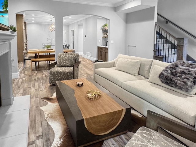 living room with sink, ornamental molding, and wood-type flooring