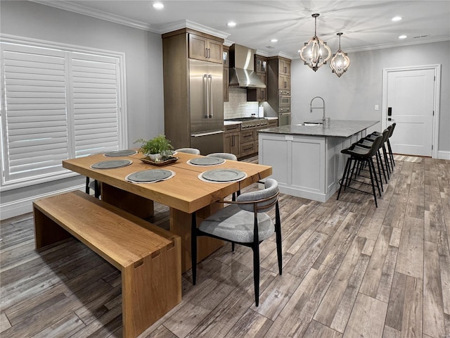 dining space with sink, light hardwood / wood-style flooring, crown molding, and a notable chandelier