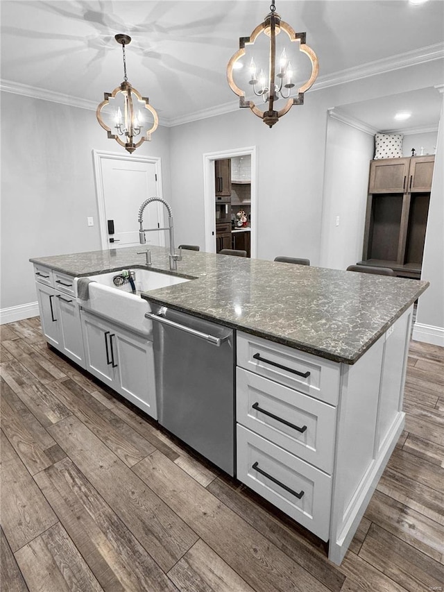 kitchen featuring dishwasher, decorative light fixtures, an inviting chandelier, and an island with sink