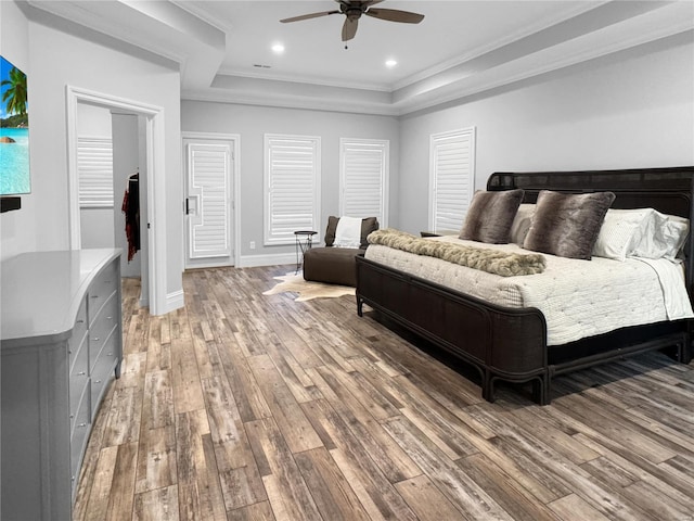 bedroom featuring ceiling fan, a raised ceiling, ornamental molding, and hardwood / wood-style floors