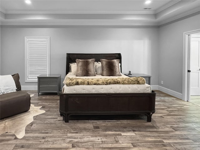 bedroom featuring hardwood / wood-style flooring, a raised ceiling, and ornamental molding