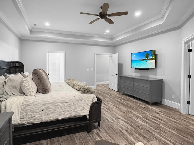 bedroom with ceiling fan, wood-type flooring, crown molding, and a tray ceiling