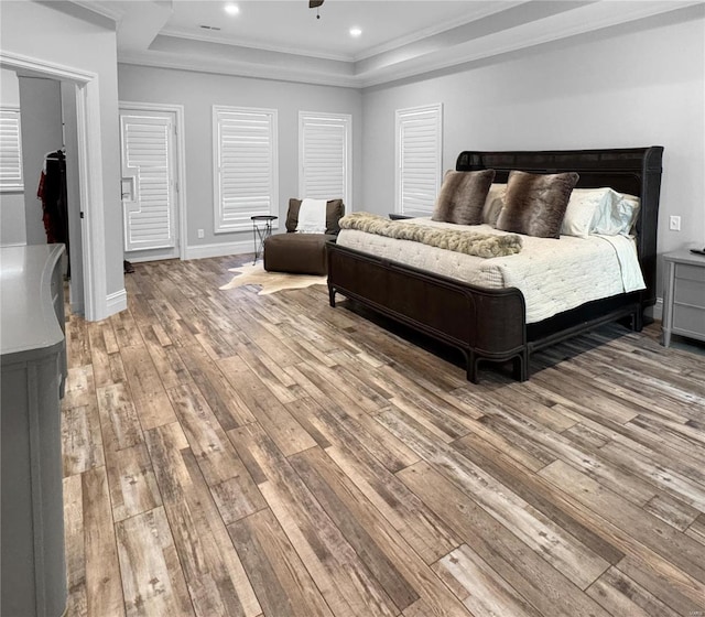 bedroom with a raised ceiling, crown molding, and light hardwood / wood-style floors