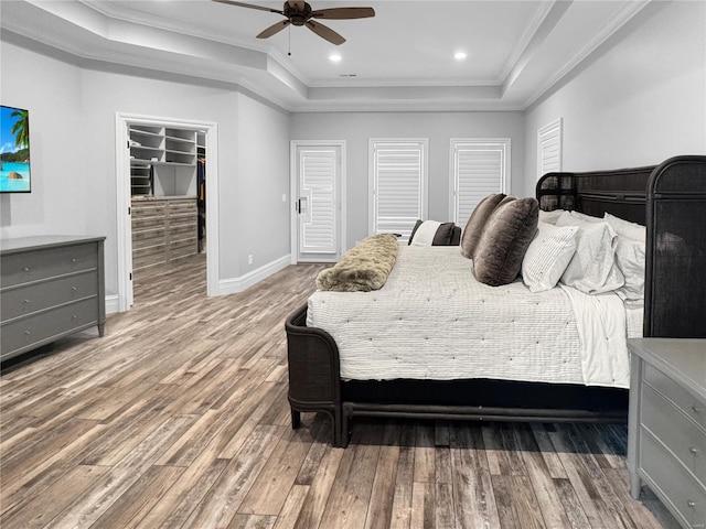 bedroom featuring ceiling fan, wood-type flooring, a tray ceiling, and crown molding