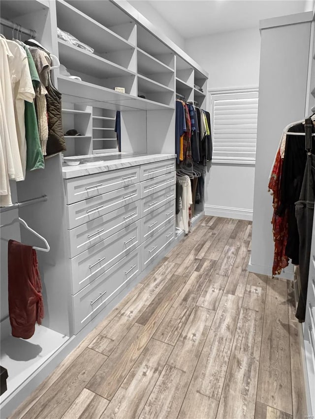 walk in closet with light hardwood / wood-style floors