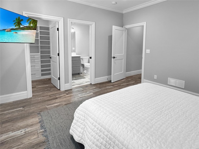 bedroom featuring ensuite bathroom, wood-type flooring, ornamental molding, a walk in closet, and a closet