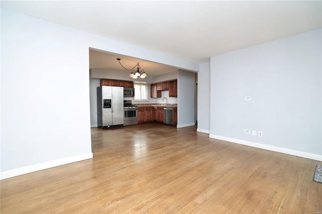 unfurnished living room with baseboards, light wood-style floors, and a notable chandelier