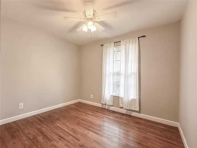 empty room with visible vents, ceiling fan, baseboards, and wood finished floors