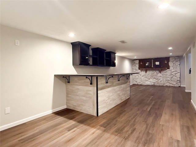 kitchen featuring dark wood-type flooring, baseboards, a peninsula, and a breakfast bar area