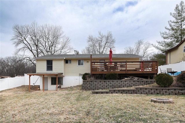 back of property with a deck, a yard, and fence