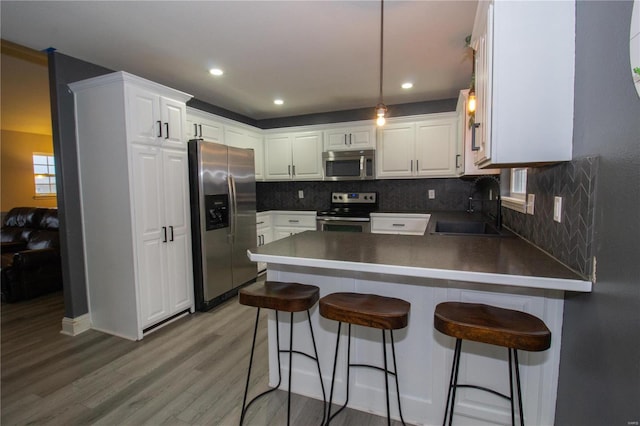 kitchen featuring sink, white cabinetry, appliances with stainless steel finishes, and a kitchen breakfast bar