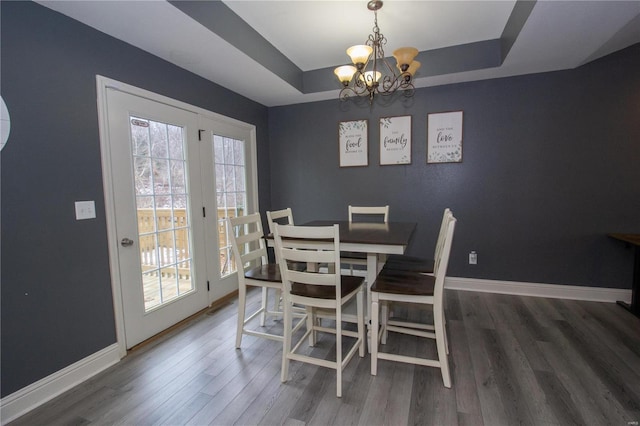 dining area with a raised ceiling, dark wood-type flooring, and a healthy amount of sunlight