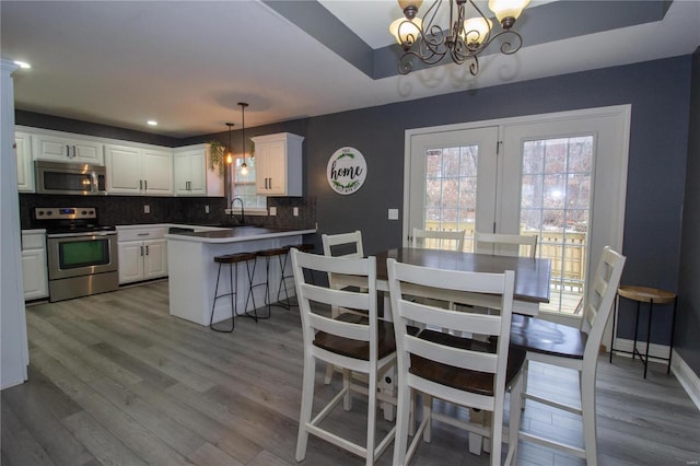 dining room with light hardwood / wood-style floors, sink, and an inviting chandelier