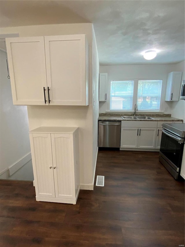 kitchen featuring stainless steel appliances, white cabinetry, sink, and dark wood-type flooring