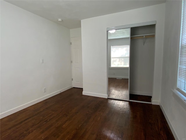 unfurnished bedroom with dark hardwood / wood-style floors and a closet