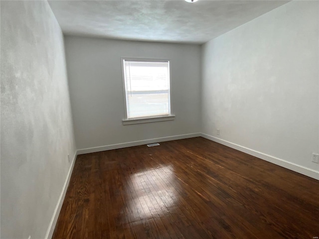 unfurnished room with dark wood-type flooring