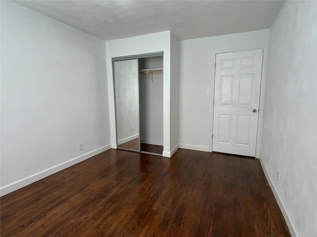 unfurnished bedroom featuring dark hardwood / wood-style flooring and a closet