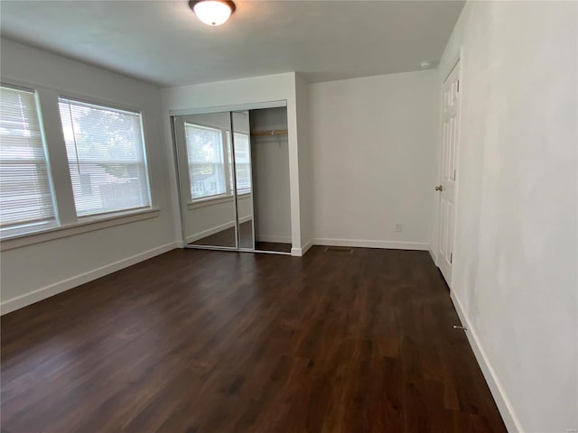 unfurnished bedroom with dark hardwood / wood-style floors and a closet