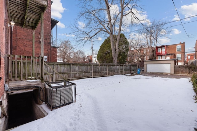 yard layered in snow with a garage, an outdoor structure, and central AC