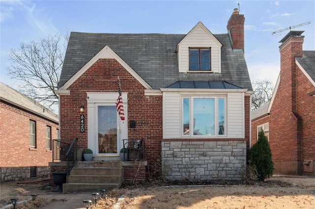 view of front of property with brick siding, stone siding, roof with shingles, and a chimney