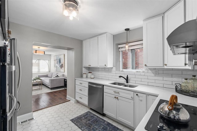 kitchen with ventilation hood, a sink, stainless steel appliances, light countertops, and backsplash