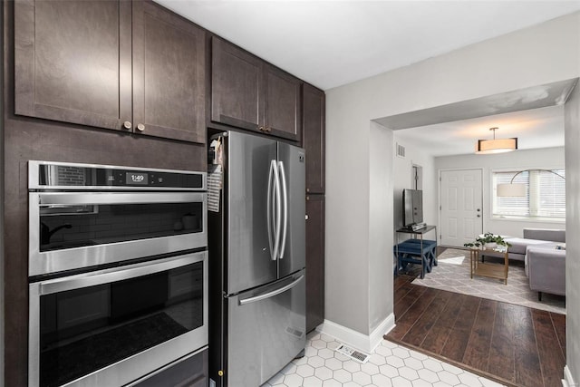 kitchen with dark brown cabinetry, baseboards, visible vents, and stainless steel appliances