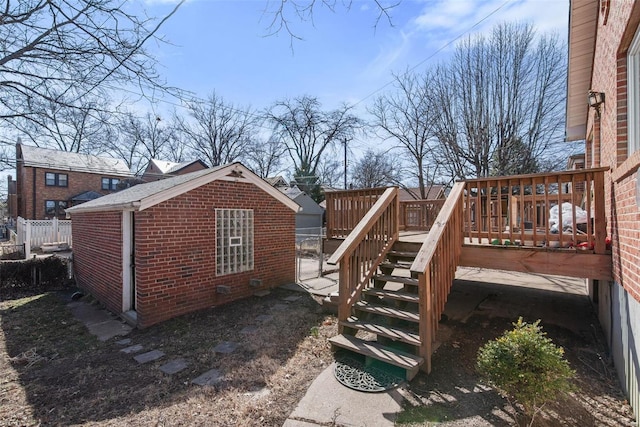 view of property exterior with a deck, stairs, fence, and brick siding