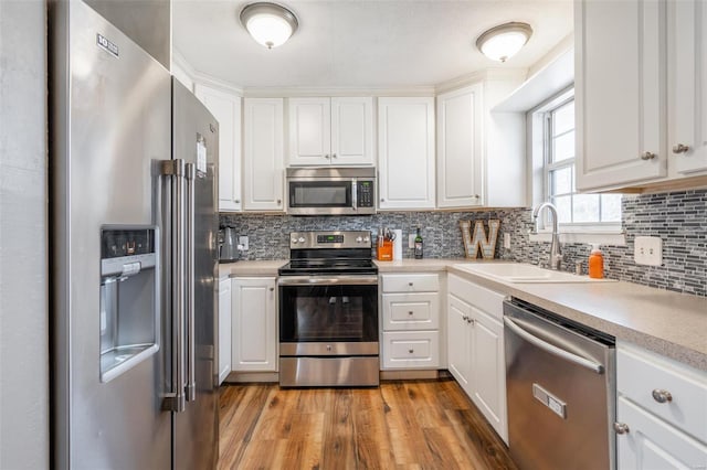 kitchen featuring light wood-type flooring, stainless steel appliances, white cabinetry, and sink