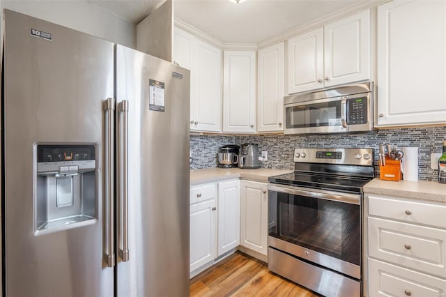 kitchen with appliances with stainless steel finishes, decorative backsplash, light hardwood / wood-style floors, and white cabinetry