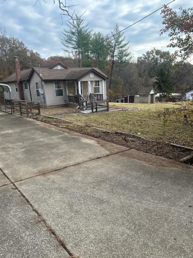 view of property exterior featuring a yard, a storage unit, and a porch