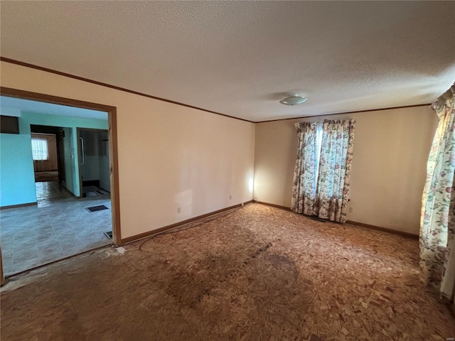 spare room with crown molding and a textured ceiling