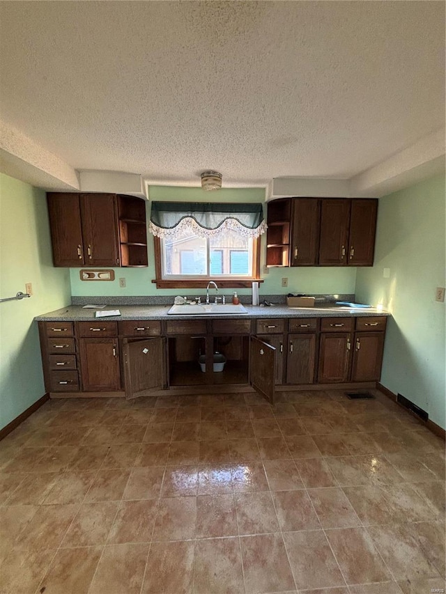 kitchen with sink, dark brown cabinets, and a textured ceiling