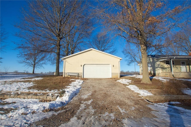 view of snowy exterior featuring an outbuilding and a garage