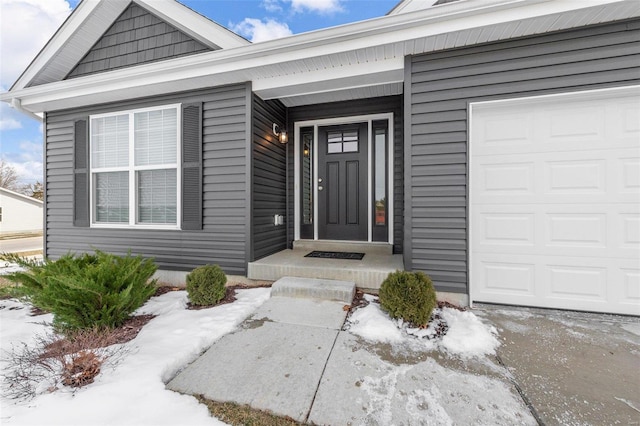 snow covered property entrance featuring a garage