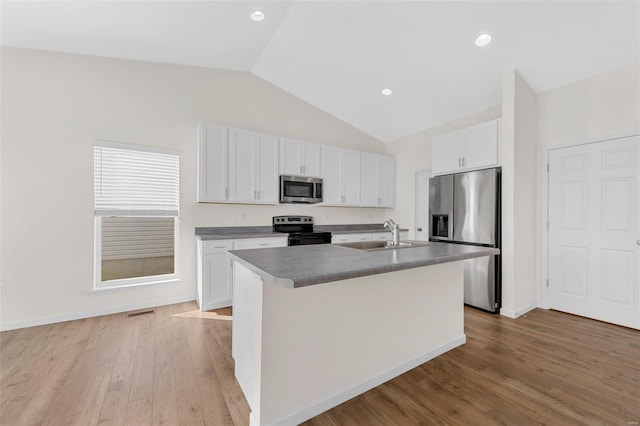 kitchen with stainless steel appliances, a sink, white cabinetry, light wood finished floors, and a center island with sink