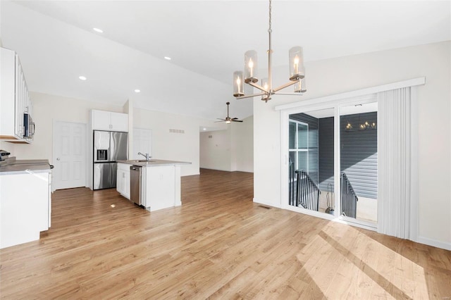 kitchen featuring open floor plan, stainless steel appliances, light wood finished floors, and a kitchen island with sink