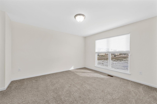 spare room featuring carpet, visible vents, and baseboards