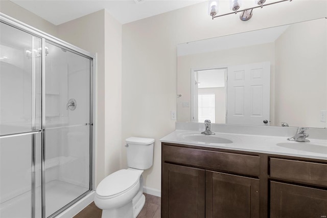 bathroom featuring a stall shower, a sink, toilet, and double vanity