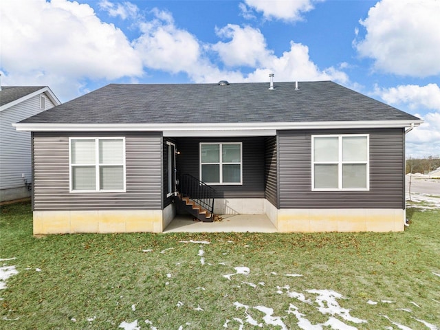 back of house featuring a shingled roof, entry steps, and a yard