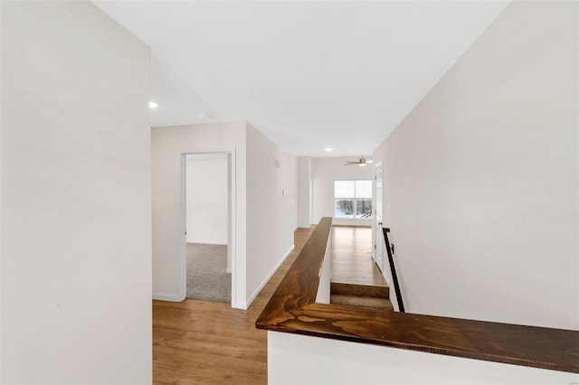 corridor featuring light wood finished floors, baseboards, and recessed lighting