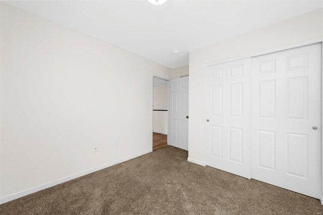 unfurnished bedroom with a closet, baseboards, and carpet flooring