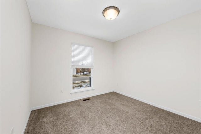 spare room with carpet floors, visible vents, and baseboards