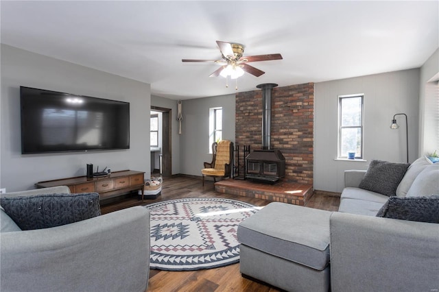 living room featuring a wood stove, ceiling fan, and dark wood-type flooring