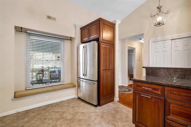 kitchen with stainless steel refrigerator, decorative light fixtures, a chandelier, dark stone counters, and light tile patterned floors